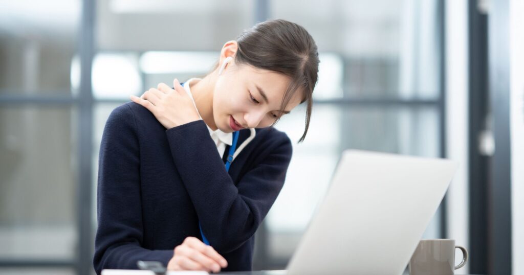 長時間のデスクワークにより頭痛を起こしている女性